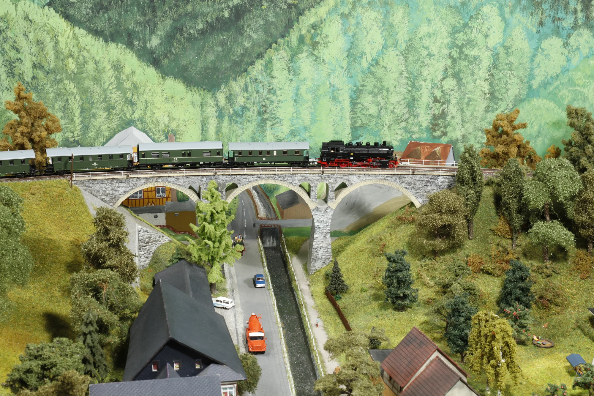 TT-Modellbahn: Güterzug auf einem steinernen Viadukt in einer detailreich gestalteten Landschaft